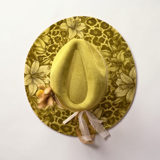 Olive green wide brim boho hat with leopard and floral engraved design displayed outdoors on tree stump